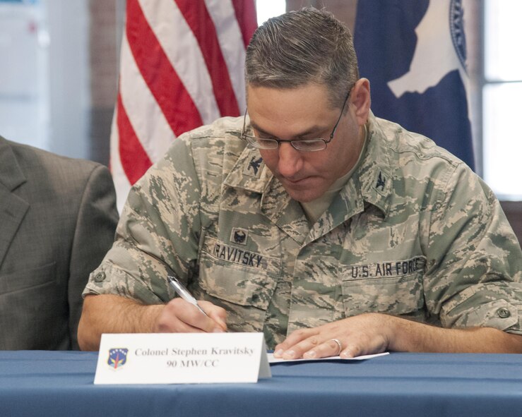 Colonel Stephen Kravitsky, 90th Missile Wing Commander, signs one of several base implementations of the Air Force Community Partnership Program in the Fall Hall Community Center on F.E. Warren Air Force Base, Wyo., Dec. 15, 2015. Kravitsky and local officials signed five documents, formalizing agreements that mutually benefit the local community and the base. (U.S. Air Force photo by Senior Airman Jason Wiese/Released)