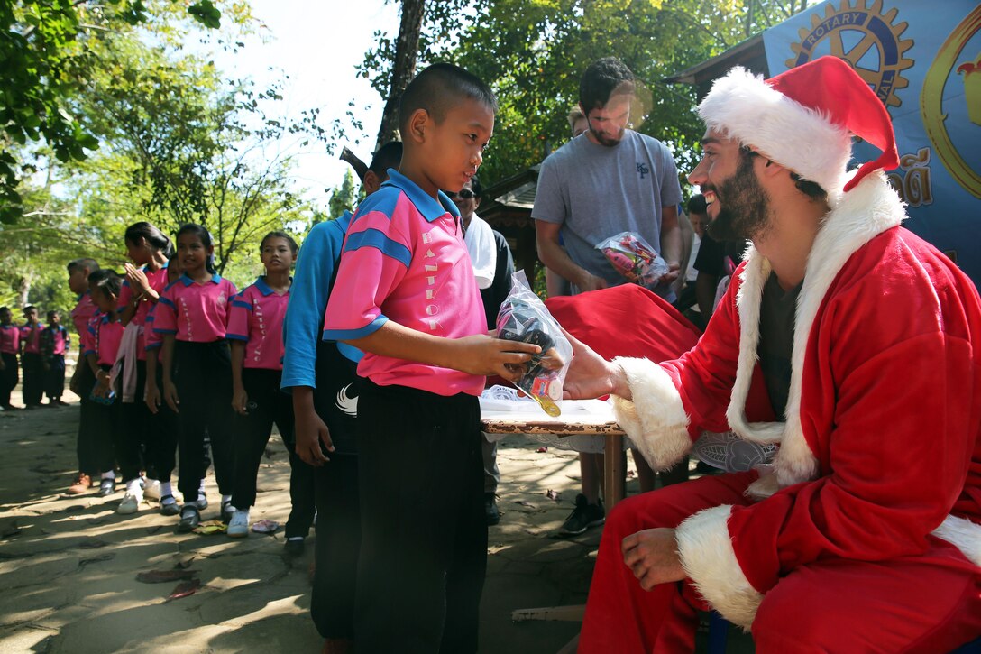 Joe Gutierrez hands out gifts to students during a community outreach event at an elementary school in Chanthaburi, Thailand, Dec. 21, 2015. Gutierrez, a midshipman cadet from the U.S. Merchant Marine Academy, is assigned to the USNS Walter S. Diehl. U.S. Navy photo by Grady T. Fontana