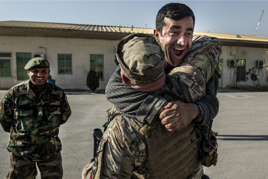 An Afghan service member jumps into the arms of U.S Air Force Master Sgt. Daniel Prosymchak near Forward Operating Base Oqab, Kabul, Afghanistan, Dec. 13, 2015. Prosymchak is assigned to the Train, Advise, Assist Command's air security forces. Air Force photo by Staff Sgt. Corey Hook