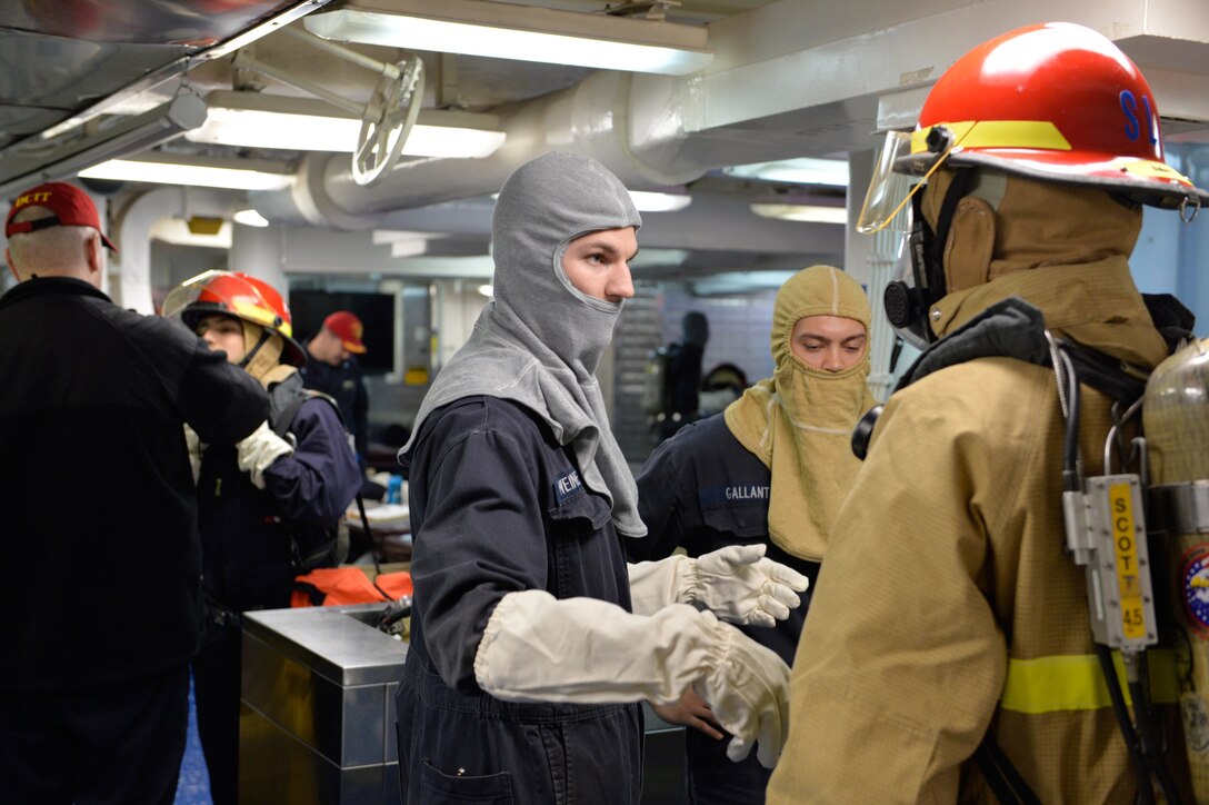 U.S. sailors put on firefighting gear and prepare to participate in a fire drill aboard the USS Ross in the Black Sea, Dec. 10, 2015. U.S. Navy photo by Petty Officer 2nd Class Justin Stumberg