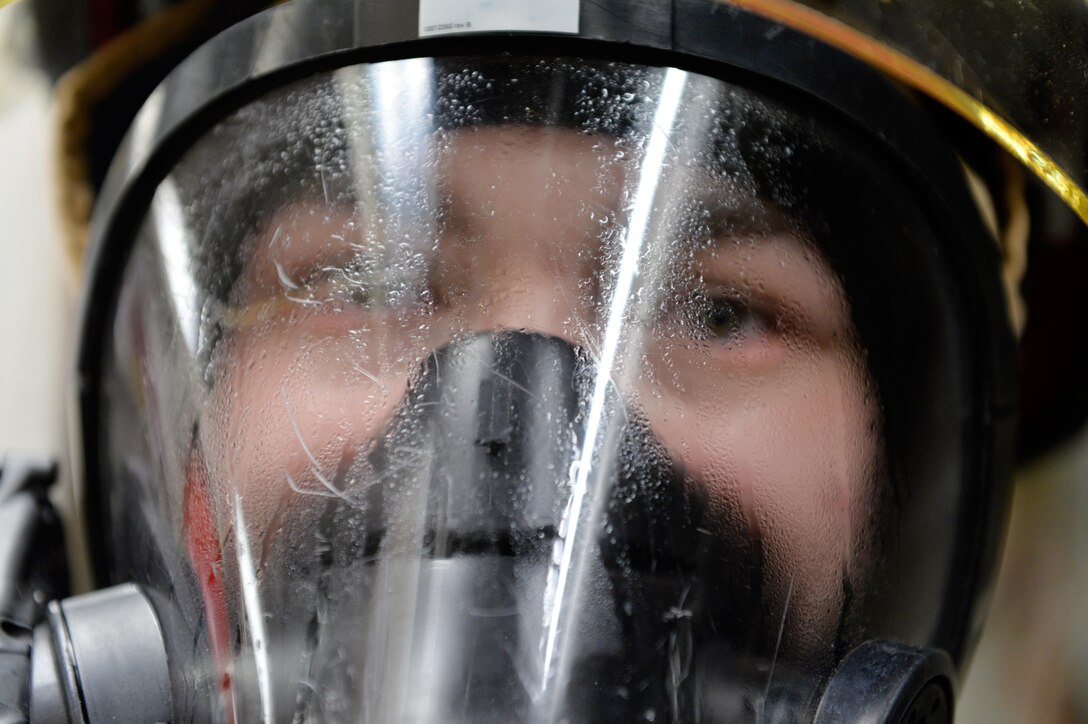 A U.S. sailor puts on a firefighting mask and prepares to participate in a fire drill aboard the USS Ross in the Black Sea, Dec. 10, 2015. U.S. Navy photo by Petty Officer 2nd Class Justin Stumberg