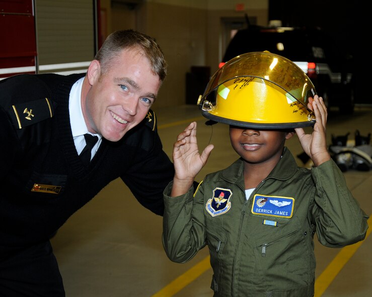 Will Omeara, 14th Civil Engineer Squadron Fire Chief, presents a hat signed by several Team BLAZE community members to Derrick James, 8-year-old Pilot for a Day participant, Dec. 22 at Columbus Air Force Base, Mississippi. He was also given a flight suit complete with nametag and patches, and took a photo in the suit with his jet, traditionally known as a “hero shot.” (U.S. Air Force photo/Sharon Ybarra)
