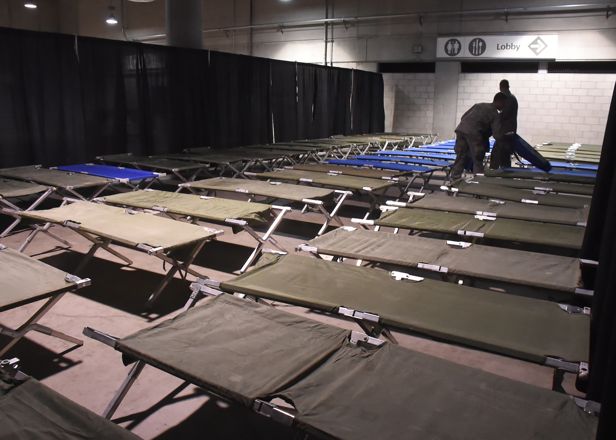 Their task nearly complete, a couple of volunteers from the Space and Missile Systems Center at Los Angeles Air Force Base in El Segundo, Calif. put the finishing touched to the Men's sleeping area inside the Los Angeles Convention Center Dec. 18, 2015 for the 2nd annual L.A. Vets Stand Down. More than 65 volunteers from SMC joined dozens of service providers from federal, state, city and county governments as well as local nonprofit partners from across Los Angeles County and the South Bay during the three-day event, billed as the largest stand down for homeless military veterans and their families to ever take place in the country. (U.S. Air Force photo/Sarah Corrice)