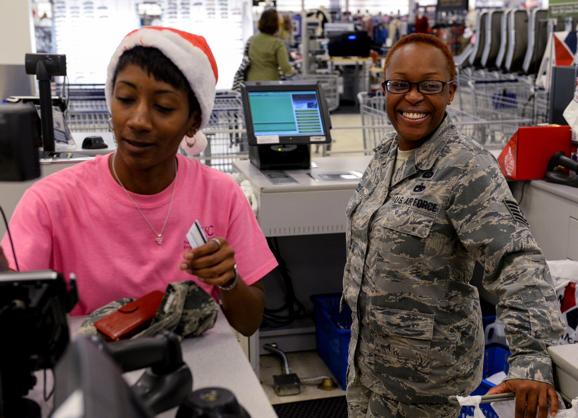 Jamila Seals, Kadena Thrift Store assistant manager and Okinawa Enlisted Spouses’ Club member, randomly makes a purchase for U.S. Air Force Tech. Sgt. Lakesha Cole, 353rd Special Operations NCO in charge of manpower organization, Dec. 21, 2015, at the Base Exchange, Kadena Air Base, Japan. Volunteers from the OESC visited various military installations on island, offering to purchase simple things such as a haircuts, meals, tanks of gas or even a cart full of groceries for enlisted family members from all U.S. branches service. (U.S. Air Force photo by Senior Airman John Linzmeier)