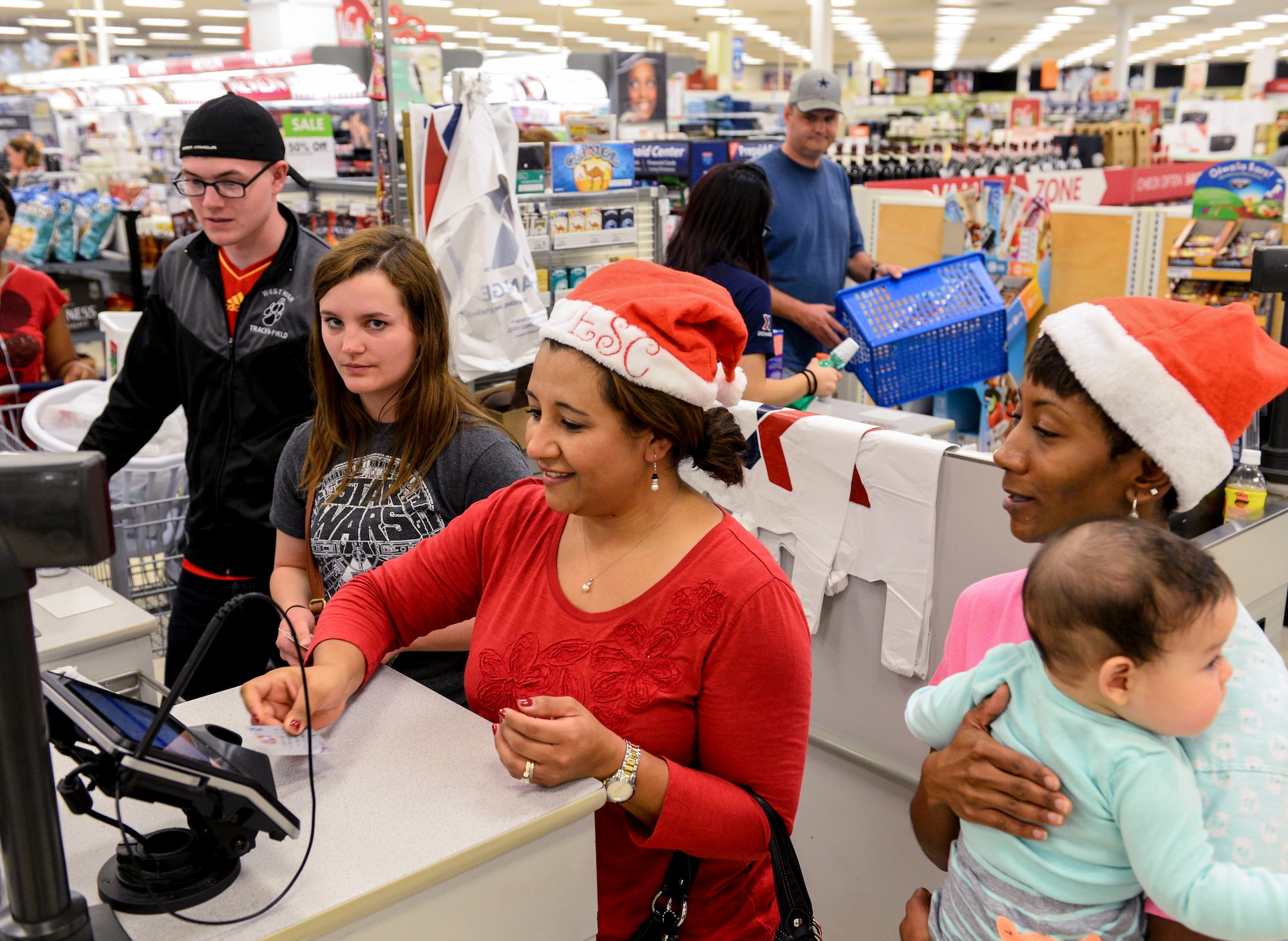 Angela Edwards, Okinawa Enlisted Spouses’ Club member, makes a purchase for patrons of the Kadena Base Exchange, Dec. 21, 2015, at Kadena Air Base, Japan. Members of the Okinawa Enlisted Spouses' Club have been surprising military families with random acts of kindness in hopes of furthering the trend of giving during the holiday season. (U.S. Air Force photo by Senior Airman John Linzmeier)