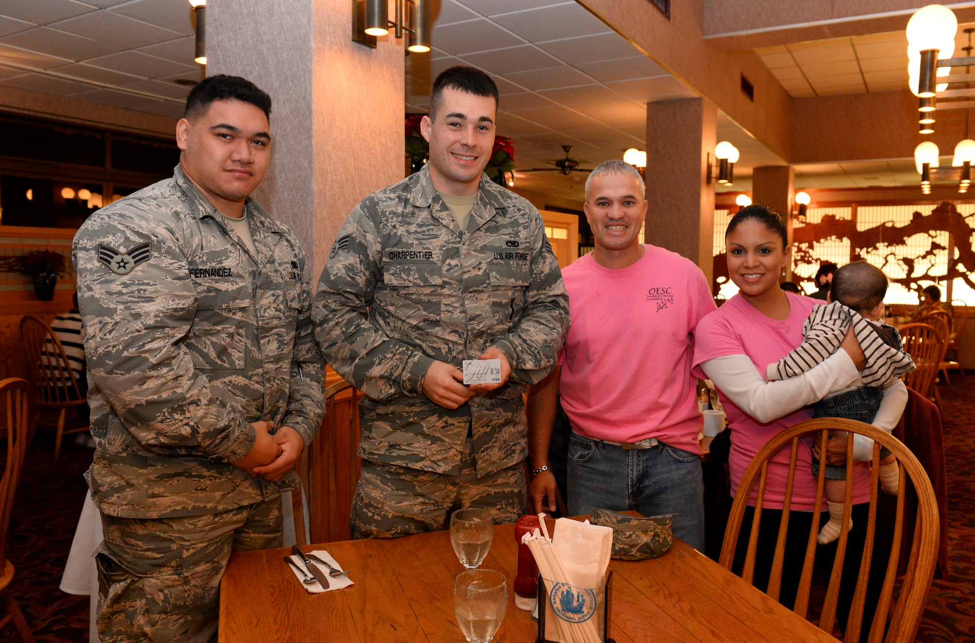 U.S. Air Force Senior Airmen Ryan Charpentier and Kameran Fernandez, 18th Maintenance Group squadron lead crew members, are randomly treated to a free meal by Victor Colon and Shyla Bowles, Okinawa Enlisted Spouses’ Club members, Dec. 28, 2015, at the Rocker NCO Club at Kadena Air Base, Japan. Members from the OESC have been committing Random Acts of Kindness for U.S. Military families throughout the holiday season in hopes of furthering the trend of giving. (U.S. Air Force photo by Senior Airman John Linzmeier) 