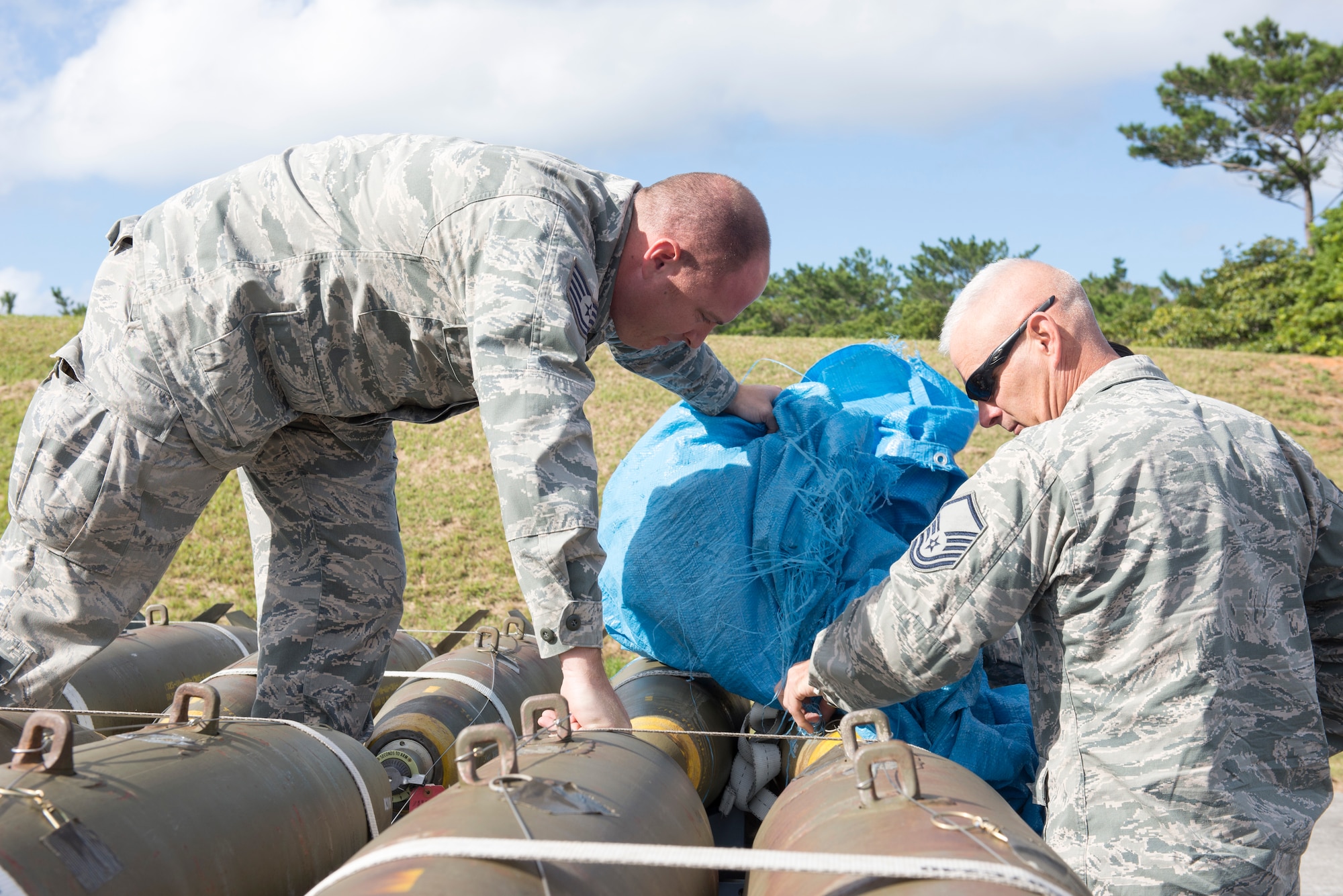U.S. Air Force U.S. Air Force Tech. Sgt. Randy Mortan, 138th Fighter Wing NCO in charge of conventional maintenance, and Master Sgt. Jim Richards, 138th Fighter Wing maintenance superintendent unwrap live bombs made during a bomb build, Dec. 18, 2015, at Kadena Air Base, Japan. The 138th Fighter Wing belongs to the Oklahoma Air National Guard and is deployed to Kadena as part of the U.S. Pacific Command’s Theater Security Package. (U.S. Air Force photo by Senior Airman Omari Bernard)