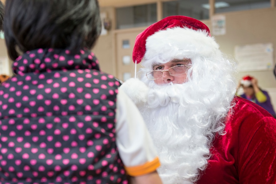 U.S. Air Force Staff Sgt. Kevin Vogt, 18th Maintenance Group quality assurance inspector, greets the children of Misaki Special Needs School dressed as Santa Claus, Dec. 17, 2015, at Okinawa City, Japan. Volunteers from the 18th Wing delivered more than $15,000 gifts donated to the Angel Tree program. (U.S. Air Force photo by Senior Airman Omari Bernard)