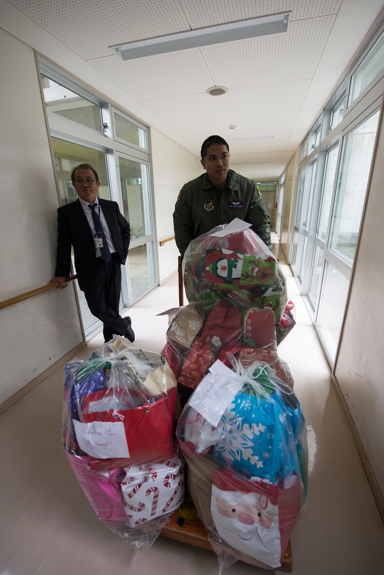 U.S. Air Force Tech. Sgt. Kent Santos, 18th Aeromedical Evacuation Squadron medical technician, delivers a cart full of donated gifts to Misaka Special Needs School, Dec. 17, 2015, at Okinawa City, Japan. More than 450 gifts were donated through the Angel Tree program by personnel on Kadena Air Base. (U.S. Air Force photo by Senior Airman Omari Bernard)
