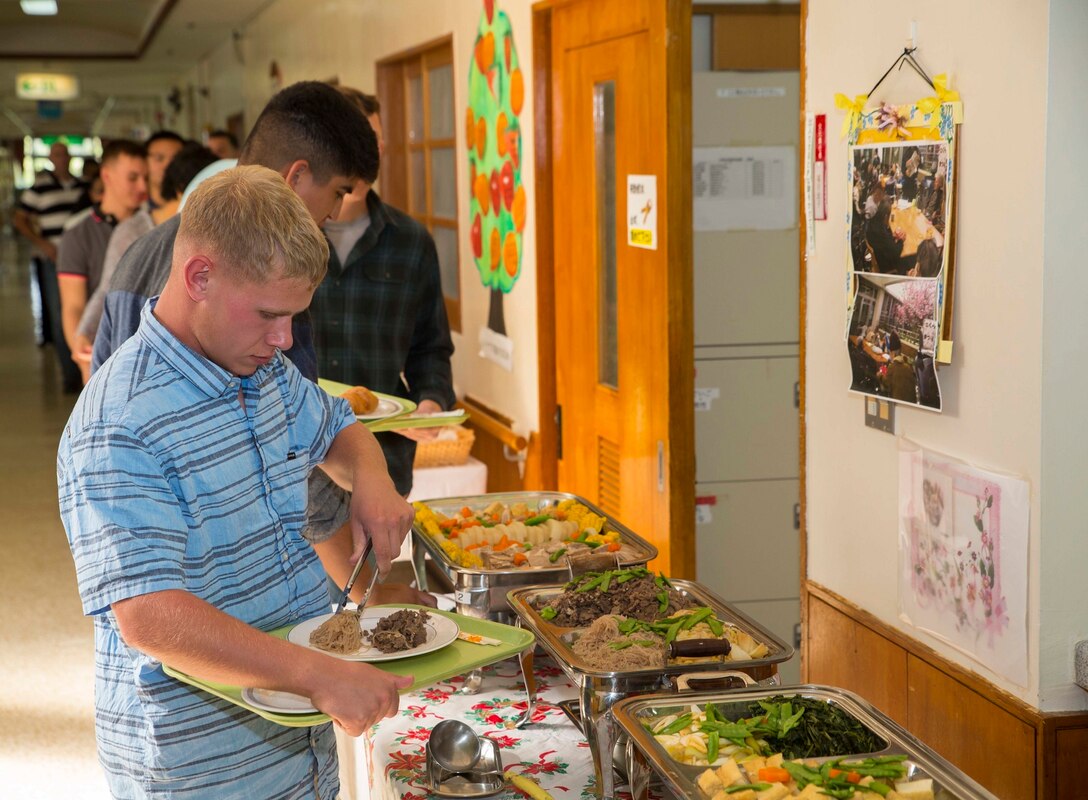 Lance Cpl. David Ryan from Tallahassee, Florida, fills his plate during a Christmas party thrown by the Hikariga Oka Nursing Home in Kin Town, Okinawa, Japan, Dec. 18, 2015. The nursing home hosts the party annually as thanks for 7th Communication Battalion’s continuous community outreach projects. Since 1994, Marines with the battalion have regularly volunteered to help maintain the home’s grounds and organized routine cleanups and maintenance. Ryan is a field radio operator with 7th Comm. Bn., III Marine Expeditionary Force Headquarters Group, III MEF.(U.S. Marine Corps Photo by Cpl. Devon Tindle/Released)