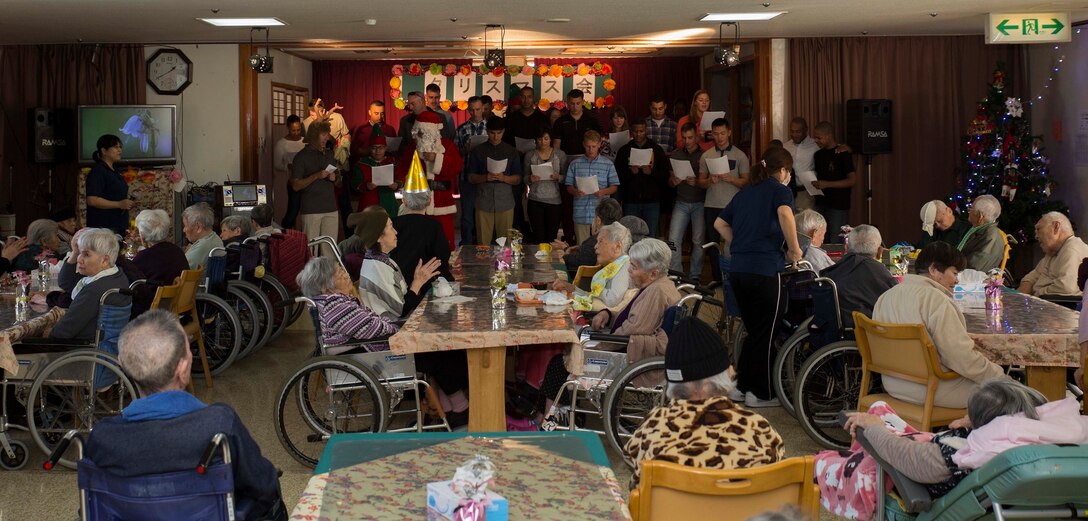 Marines with 7th Communication Battalion sing Christmas carols to the residents at Hikariga Oka Nursing Home during a Christmas Party thrown by the nursing home for the Marines at Hikariga Oka Nursing Home in Kin Town, Okinawa, Japan, Dec. 18, 2015.The nursing home hosts the Christmas party annually to pay thanks for the battalion’s continual community relations projects. Since 1994 Marines with the battalion regularly volunteers regularly to help maintain the home’s grounds of the home and conduct organize routine cleanups and maintenance. The Marines are with 7th Comm. Bn., III Marine Expeditionary Force Headquarters Group, III MEF. (U.S. Marine Corps Photo by Cpl. Devon Tindle/Released)