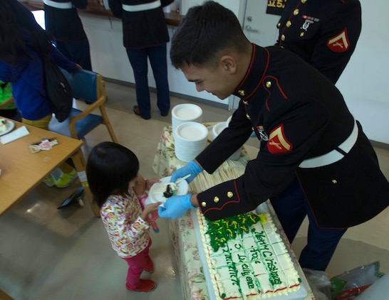 Lance Cpl. Tony McCandless, right, hands out cake to kids Dec. 19 at the Kin Town Social Welfare Center, Okinawa, Japan. Marines organized a toy drive through the Kin Town Single Parent Association to give back to their community by handing out gifts and cake to the children. McCandless is a radio maintainer with 3rd Intelligence Battalion, III Marine Headquarters Group, III Marine Expeditionary Force. (U.S. Marine Corps photo by Cpl. Isaac Ibarra/Released)