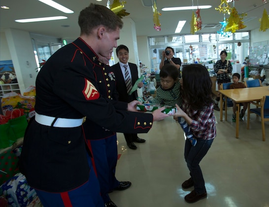Cpl. Zachariah Mercer hands a present to a child Dec. 19 at the Kin Town Social Welfare Center, Okinawa, Japan. Marines organized a toy drive through the Kin Town Single Parent Association to give back to their community by handing out gifts and cake to the children. Mercer is a surveillance sensor operator with 3rd Intelligence Battalion, III Marine Headquarters Group, III Marine Expeditionary Force. (U.S. Marine Corps photo by Cpl. Isaac Ibarra/Released)