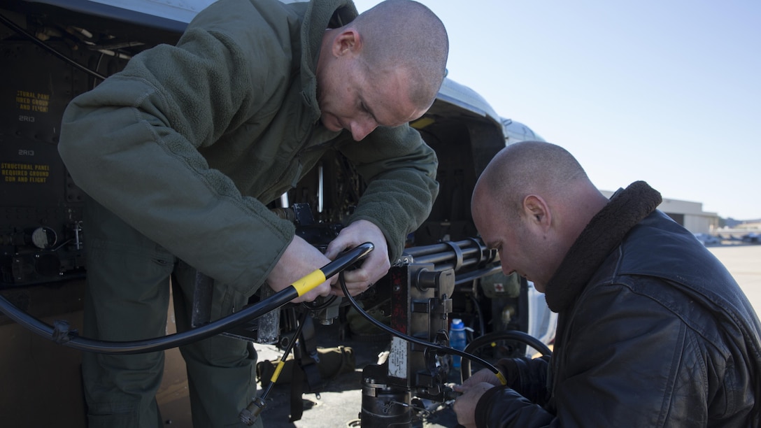 Two combat marksmanship trainer instructors with Marine Light Attack Helicopter Squadron 303, prepare an M134 GAU-17 Minigun prior to a formation flight and aerial gunnery shoot at Marine Corps Air Station Camp Pendleton, California, Dec. 17. Marines with HMLAT-303 flew a formation flight and conducted an aerial gunnery to shoot to give students the opportunity to refine basic skills needed to operate in the Fleet Marine Force.