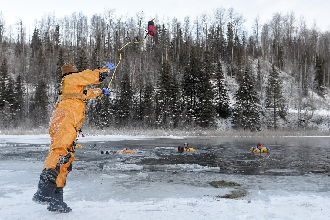 Air Force Lt. Col. Joseph Cook tosses a throw bag to firefighters in a frigid lake during cold water and ice rescue training on Joint Base Elmendorf-Richardson, Alaska, Dec. 20, 2015. Cook is squadron commander of the 673rd Civil Engineer Squadron. Air Force photo by Alejandro Pena