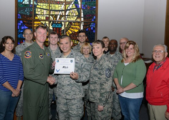 Capt. Thienan Tran, center, 47th Flying Training Wing chaplain, poses with Col. Thomas Shank, left, 47th FTW commander, and Chief Master Sgt. Teresa Clapper, 47th FTW command chief, after accepting the “XLer of the Week” award, here, Dec. 16, 2015. The XLer is a weekly award chosen by wing leadership and is presented to those who consistently make outstanding contributions to their unit and Laughlin. (U.S. Air Force photo by Senior Airman Jimmie D. Pike)