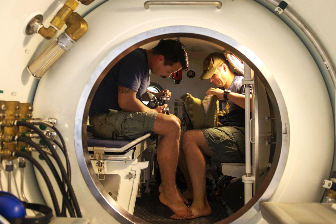 Navy Petty Officers 2nd Class Jonathan Miranda, left, and Ryan McGovern inspect a medical kit inside a double-lock recompression chamber system in Bahrain, Dec. 22, 2015. Miranda is a diver and McGovern is a hospital corpsman. U.S. Navy photo by Petty Officer 2nd Class Shannon Burns