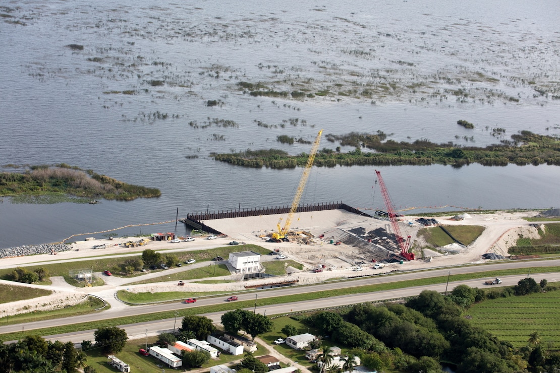 With Lake Okeechobee in the background, crews work to replace a water control structure, or "culvert" in Herbert Hoover Dike along Highway 27 near Clewiston.  The culvert replacements ongoing require significant preparation of the site, to include installation of a temporary cofferdam to hold back water while crews work on the earthen structure.