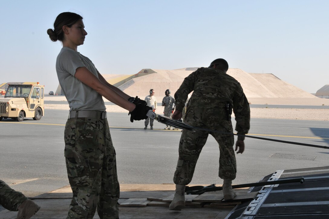 A U.S. soldier pulls on a cable hooked up to an AH-64 Apache helicopter to be offloaded from a C-17 Globemaster aircraft on Al Udeid Air Base, Qatar, Dec. 13, 2015. U.S. Air Force photo by Tech. Sgt. Terrica Y. Jones