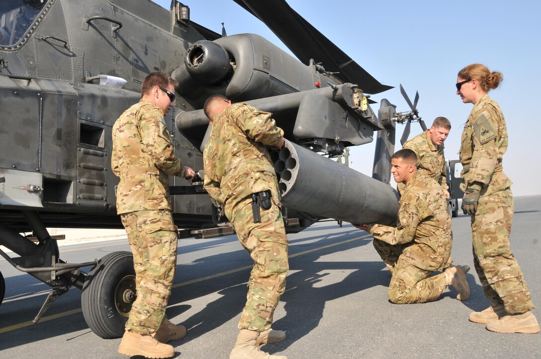 U.S. soldiers attach a laser-guided 2.75 rocket pod to an AH-64 Apache helicopter on Al Udeid Air Base, Qatar, Dec. 13, 2015. U.S. Air Force photo by Tech. Sgt. Terrica Y. Jones