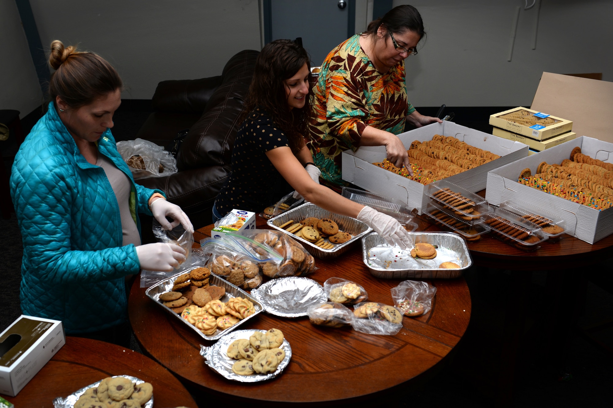 Joanna Livaudais, spouse of TSgt. Paul Livaudais, Tricia Walters, spouse of 2nd Lt. Casey Walters, and Denice Tilley, the community program director, bag the many cookies donated to the 2015 Colossal Cooke Drive. The cookies will be distributed to Airmen in Training for the holiday season. (U.S. Air Force photo/2nd Lt. Brittany Curry)
