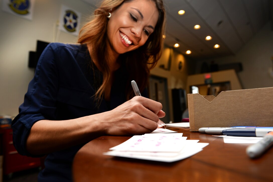 Kat Hedden, spouse of Chief Master Sgt. Benjamin Hedden, 80th Flying Training Wing command chief master sergeant, writes personalized messages that will accompany every bag of cookies handed out to Airmen. Every message, whether written by a key spouse or decorated by local elementary students, is meant to bring holiday cheer to the Airmen in Training as they prepare for the holiday break. (U.S. Air Force photo/2nd Lt. Brittany Curry)