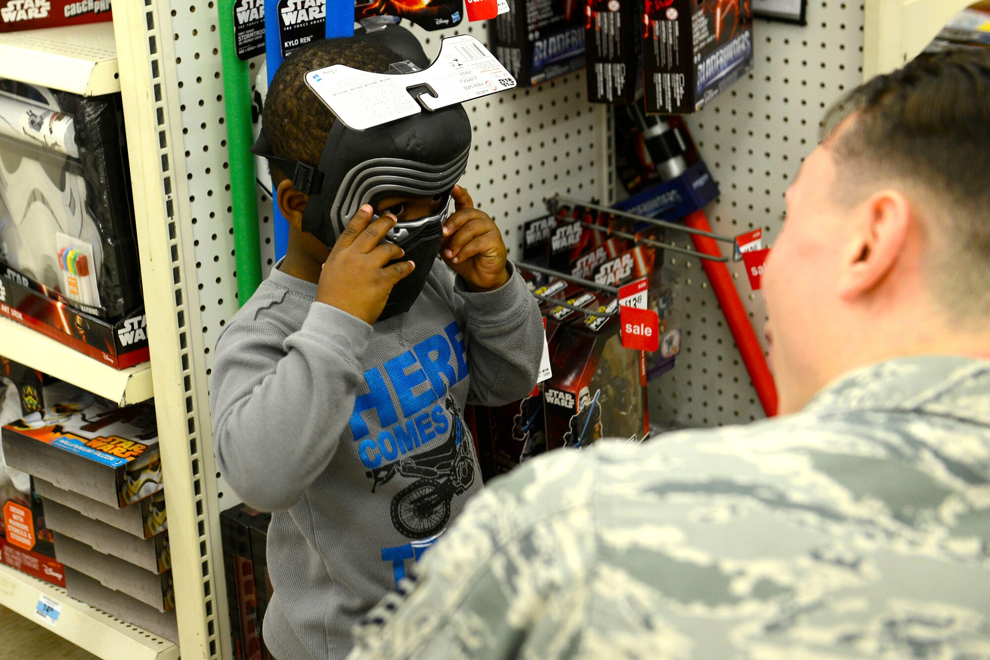 A child from the John K. Crosswell Home for Children, Sumter, S.C., tries on a mask during a Shop with a Cop event at a local store in Sumter, S.C., Dec. 21, 2015. After Christmas shopping, the children received goodie bags to go along with their presents. (U.S. Air Force photo by Airman 1st Class Christopher Maldonado)
