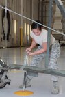 Senior Airman Bianca Alcantara, 22nd Medical Operations Squadron medical technician, adjusts a maintenance stand Nov. 12, 2015, at McConnell Air Force Base, Kan. Members of the 22nd MDOS paid a visit to the 22nd Aircraft Maintenance Squadron to perform some of the basic tasks a maintainers, perform in order to create profiles dictated by their day-to-day jobs. (Courtesy Photo)