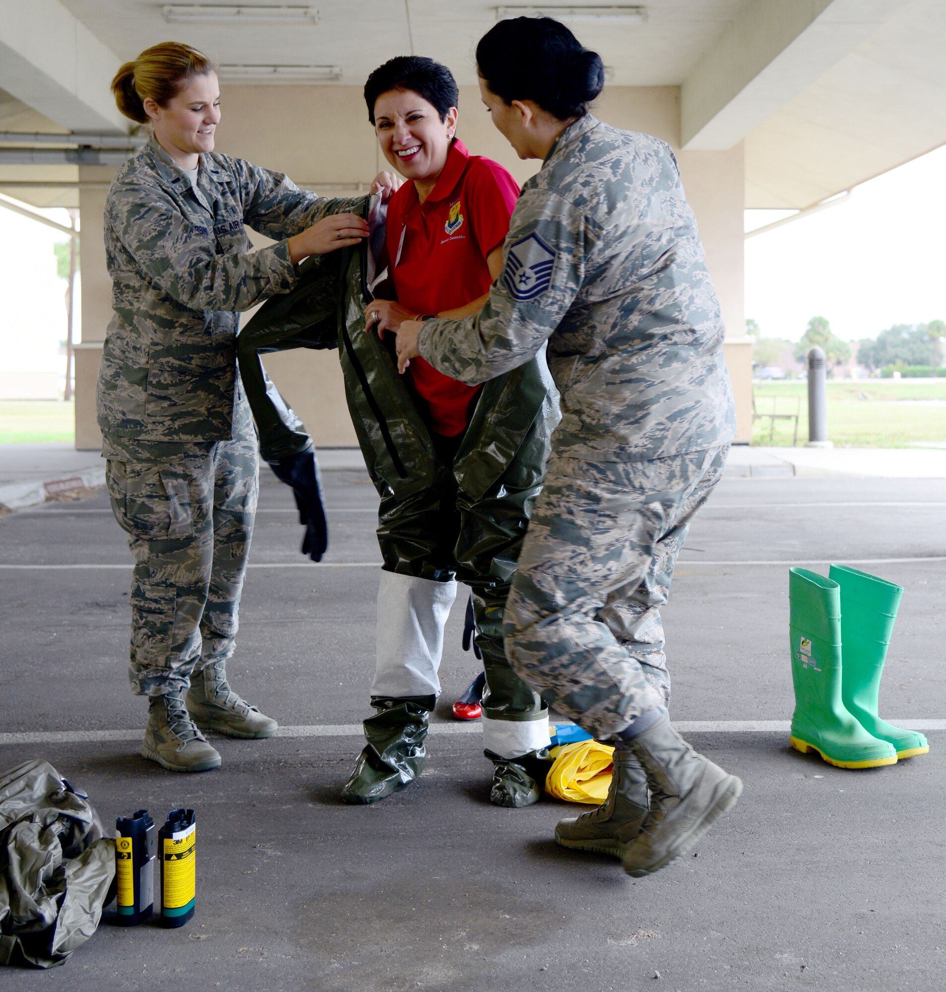 1st Lt. Jessica Robbins, a physician’s assistant assigned to the 6th Medical Operation Squadron, and Master Sgt. Jamie Meadows Valley, the dental logistics NCO in charge of the 6th Dental Squadron, assist Yvette Segura, the honorary commander assigned to 6th Operations Group, with putting on a decontamination suit during an immersion at the 6th Medical Group at MacDill Air Force Base, Fla., Dec. 18, 2015. The honorary commanders from the 6th Air Mobility Wing and the 927th Air Refueling Wing were invited to take part in the day’s activities. (U.S. Air Force photo by Staff Sgt. Brittany Liddon)