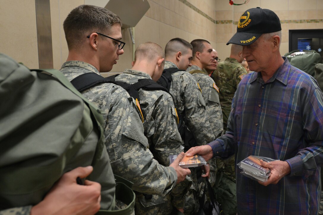 Mike Carkhuff, volunteer for the Regimental Memorial Chapel, hands out gifts from the chapel to 128th Aviation Brigade Advanced Individual Training students during their exodus departure at Fort Eustis, Va., Dec. 18, 2015. The exodus was established as a way for students and cadre to take leave during the holiday season as instruction is paused during that time. (U.S. Air Force photo by Staff Sgt. Natasha Stannard)
