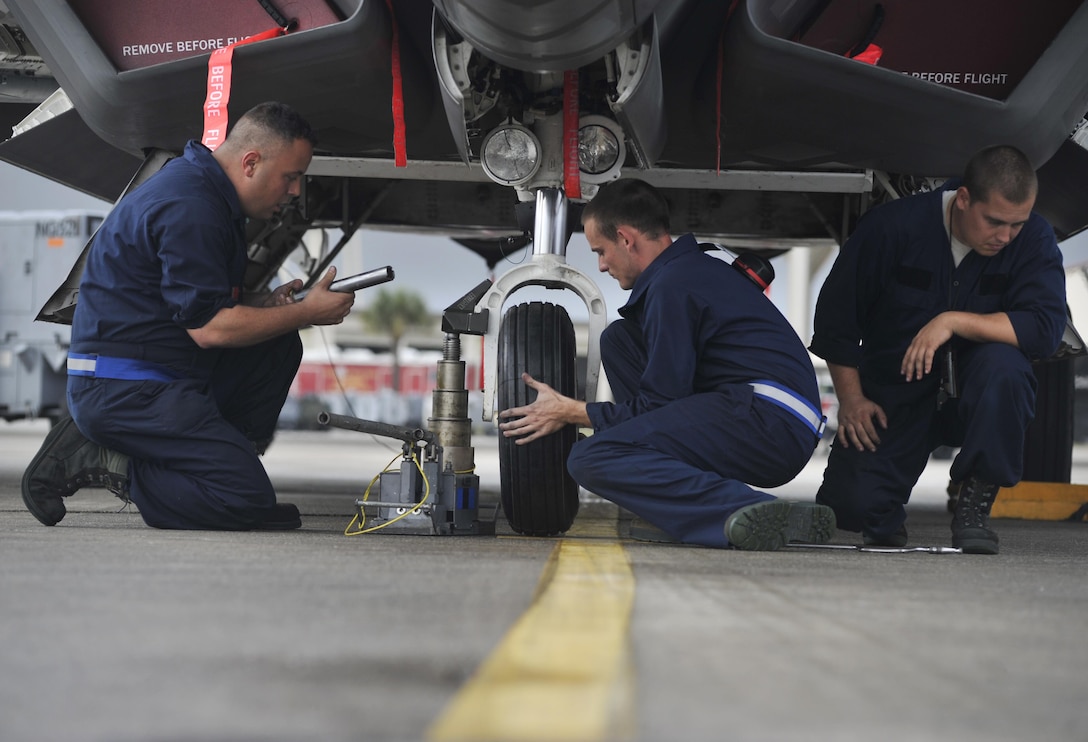 Air Force Senior Airman Seth Keadle, center, mounts a tire on an F-22 Raptor aircraft on Tyndall Air Force Base, Fla., Dec. 17, 2015. Keadle is a crew chief assigned to the 95th Aircraft Maintenance Unit. U.S. Air Force photo by Senior Airman Sergio A. Gamboa
