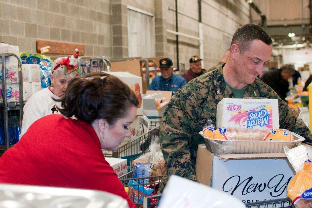 Stephanie Taber, Family Readiness program trainer and Col. Joseph Murray, base commander, join 17 members of the National Sojourners Quantico Chapter 44 during their annual Christmas Food Basket program at the Quantico Marine Corps Base Commissary aboard Marine Corps Base Quantico.