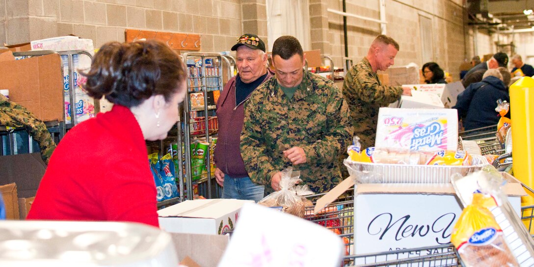 Stephanie Taber, Family Readiness program trainer; Col. Joseph Murray, base commander; and Col. Allen Broughton, chief of staff, Marine Corps National Capital Region/Marine Corps Base Quantico, join 17 members of the National Sojourners Quantico Chapter 44 during their annual Christmas Food Basket program at the Quantico Marine Corps Base Commissary aboard Marine Corps Base Quantico.