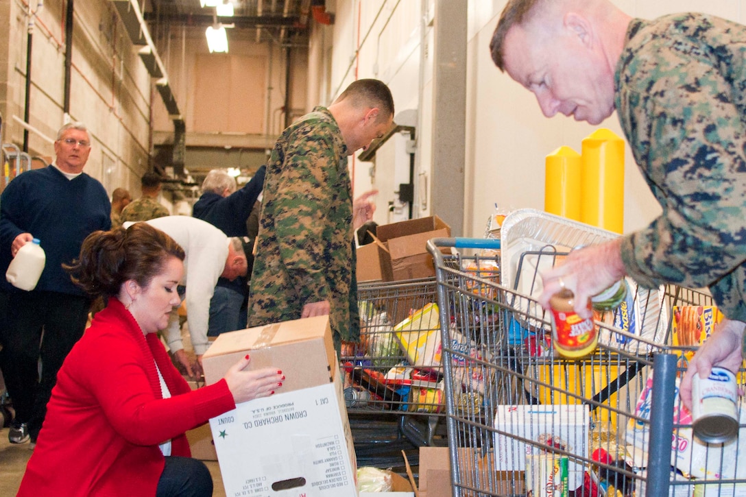 Stephanie Taber, Family Readiness program trainer; Col. Joseph Murray, base commander; and Col. Allen Broughton, chief of staff, Marine Corps National Capital Region/Marine Corps Base Quantico, join 17 members of the National Sojourners Quantico Chapter 44 during their annual Christmas Food Basket program at the Quantico Marine Corps Base Commissary aboard Marine Corps Base Quantico.