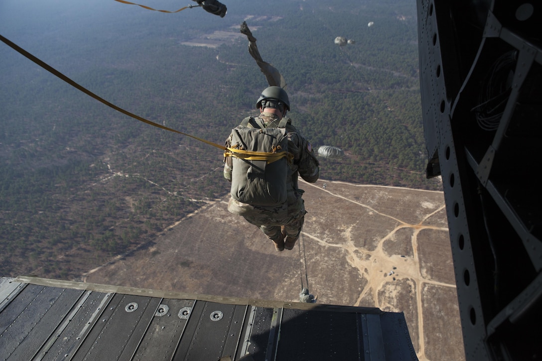 U.S. Army paratrooper exits a CH-47 aircraft for an airborne operation onto Luzon Drop Zone during Operation Toy Drop at Camp Mackall, N.C., Dec. 10, 2015. Operation Toy Drop is the world's largest combined airborne operation with seven partner-nation paratroopers participating and allows Soldiers the oppurtunity to help children in need receive toys for the holidays. (U.S. Army photo by Pfc. Sharell Madden/Released)