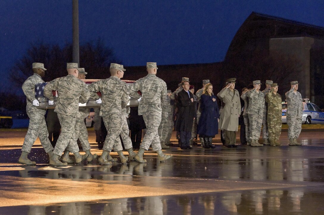 Defense Secretary Ash Carter, center, renders honors as an Air Force carry team transfers the remains of Air Force Staff Sgt. Chester J. McBride during a dignified transfer on New Castle Air National Guard Base in New Castle, Del., Dec. 23, 2015. McBride was assigned to the Air Force Office of Special Investigations, Detachment 405. U.S. Air Force photo by Roland Balik