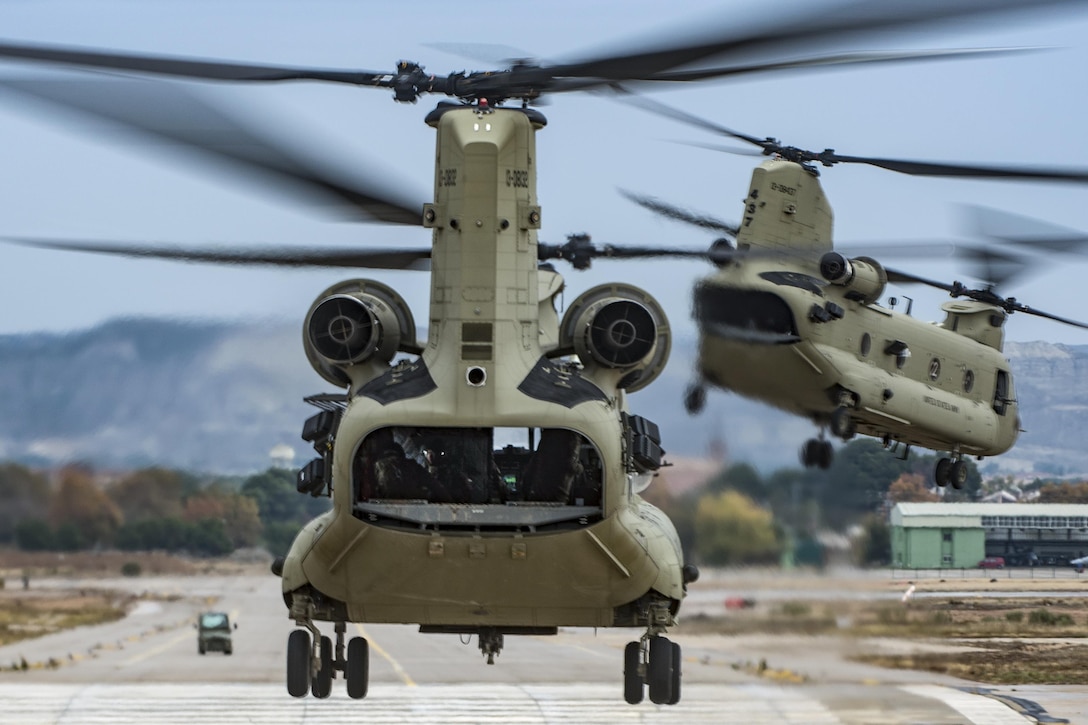 Two CH-47F Chinook helicopters take off en route to retrieve air assault troops to prepare for an air assault mission as part of Trident Juncture 2015, a NATO exercise, in Zaragoza, Spain, Nov. 3, 2015.  The helicopters are assigned to Company H, 1st Battalion, 214th Aviation Regiment, 12th Combat Aviation Brigade. U.S. Army photo by Sgt. Thomas Mort