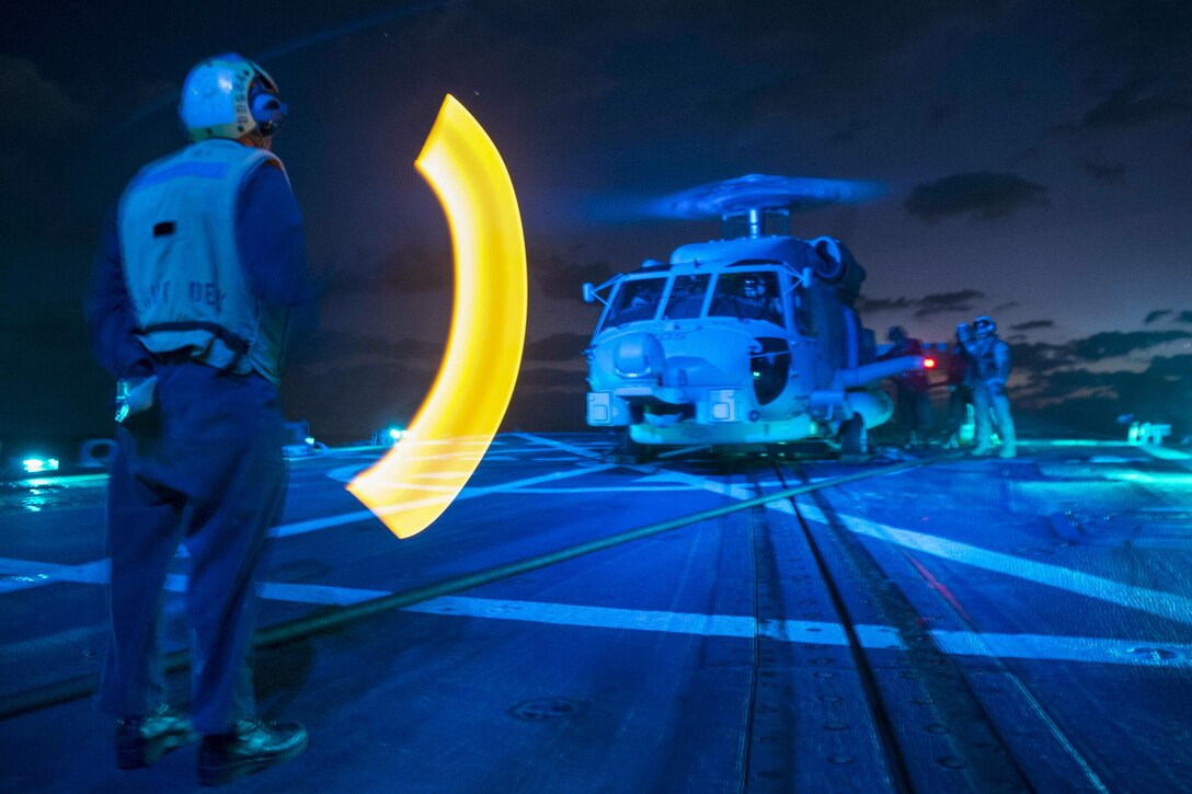 U.S. Navy Petty Officer 2nd Class K. Butler signals an MH-60R Seahawk helicopter as it refuels aboard the guided-missile destroyer USS Bulkeley in the Gulf of Aden, Dec. 19, 2015. Butler is a boatswain's mate assigned to Maritime Strike Squadron 72. The Bulkeley is supporting maritime security operations and theater security cooperation efforts in the 5th Fleet area of responsibility. U.S. Navy photo by Petty Officer 2nd Class M. J. Lieberknecht