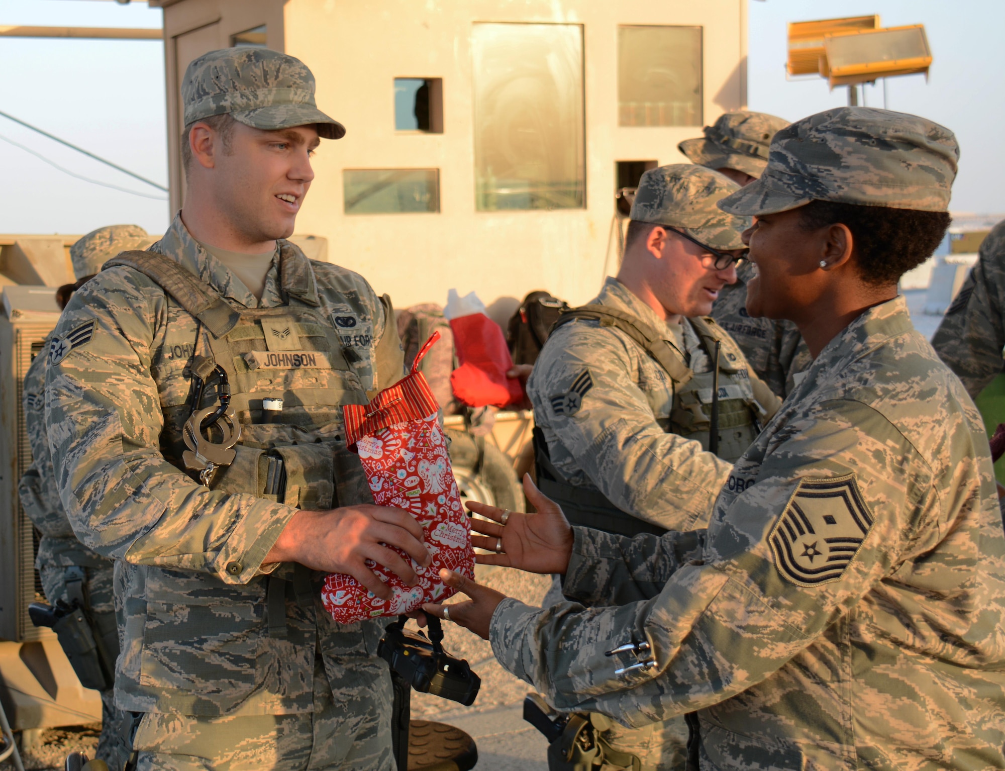 Senior Master Sgt. Temekia Clinkscales 379th Expeditionary Maintenance Squadron first sergeant, delivers a holiday stocking filled with candy, games and Christmas cards to a security forces airman at Al Udeid Air Base, Qatar Dec. 23. Clinkscales said the first sergeants decided to deliver the stockings to security forces Airmen to thank them for all they do to keep people safe. (U.S. Air Force photo by Tech. Sgt. James Hodgman/Released) 