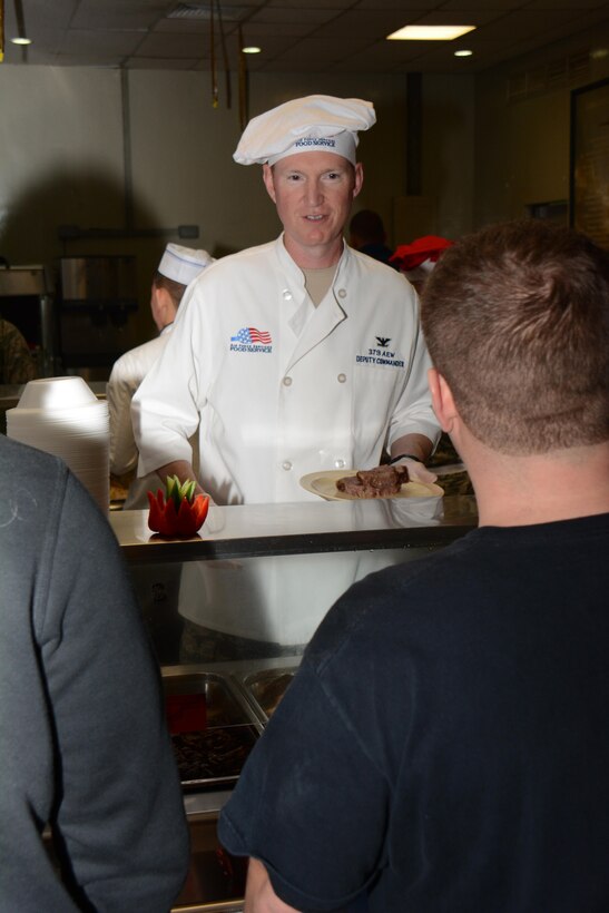 Col. Stuart Newberry, 379th Air Expeditionary Wing vice commander, serves lunch to service members at the Independence Dining Facility at Al Udeid Air Base, Qatar Dec. 25. Newberry joined several members of AUAB leadership in the holiday tradition. The holiday menu featured lobster, turkey and a variety of deserts including pie and ice cream. (U.S. Air Force photo by Tech. Sgt. James Hodgman/Released)