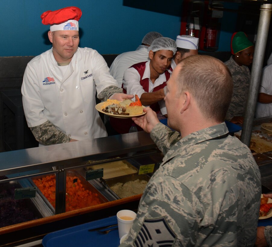 Col. Charles McFarland, 379th Expeditionary Maintenance Group commander, serves food to service members at the Manhattan Dining Facility during the Christmas lunch service at Al Udeid Air Base, Qatar Dec. 25. McFarland joined several members of AUAB leadership in the holiday tradition. The holiday menu featured lobster, turkey and a variety of deserts including pie and ice cream. (U.S. Air Force photo by Tech. Sgt. James Hodgman/Released)