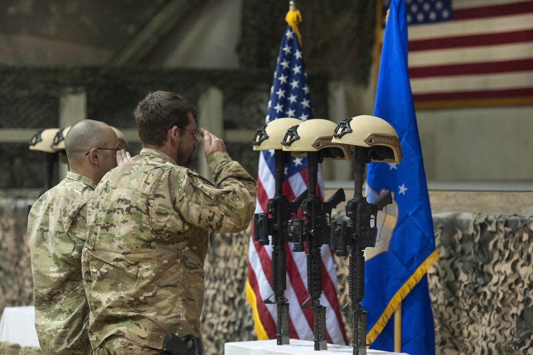 U.S. service members render honors as others pay their respects during a ceremony on Bagram Airfield, Afghanistan, Dec. 23, 2015, to honor six airmen killed in a vehicle bomb attack on their patrol outside Bagram. U.S. Air Force photo by Tech. Sgt. Robert Cloys