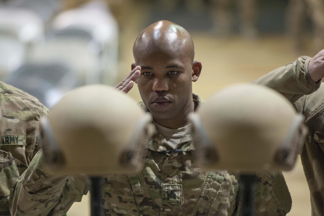 A U.S. service member renders honors as other troops pay their respects during a ceremony on Bagram Airfield, Afghanistan, Dec. 23, 2015, to honor six airmen killed in a vehicle bomb attack on their patrol outside Bagram. U.S. Air Force photo by Tech. Sgt. Robert Cloys