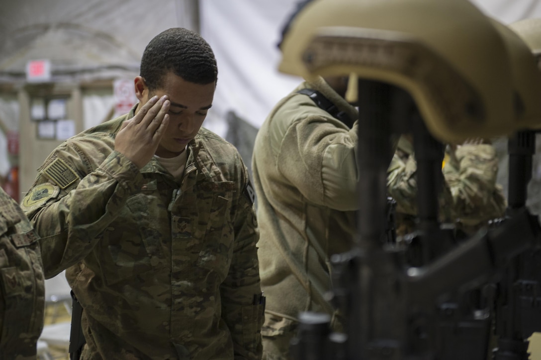 A U.S. airman renders honors as others pay their respects during a ceremony on Bagram Airfield, Afghanistan, Dec. 23, 2015, to honor six airmen killed in a vehicle bomb attack on their patrol outside Bagram. U.S. Air Force photo by Tech. Sgt. Robert Cloys