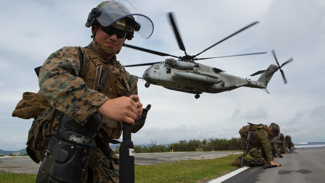 Cpl. Jordan Canchola, an artillery gunner with Golf Battery, Battalion Landing Team 1st Battalion, 5th Marines, 31st Marine Expeditionary Unit, takes a knee to shield himself from the rotor wash of a CH-53E Super Stallion helicopter at Camp Courtney in Okinawa, Japan, Dec. 15, 2015. The battery was training to distribute food and water as part of a humanitarian assistance and disaster relief operation when the crowd, played by other Marines, became unruly. A quick reaction force was called to help restore order and continue to distribute supplies. The HADR training was conducted as part of the 31st MEU’s Marine Expeditionary Unit Exercise. Cpl. Canchola is from Hollister, California.
