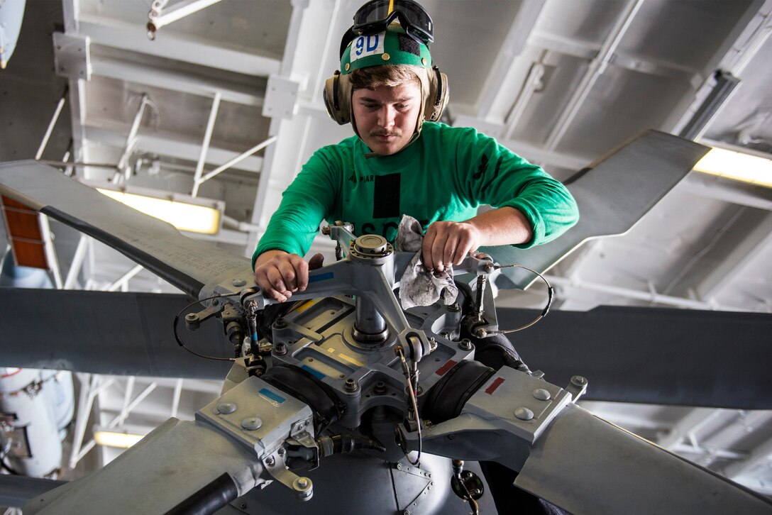 A sailor cleans the tail rotor of an MH-60S Sea Hawk helicopter in the hangar bay of the aircraft carrier USS Harry S. Truman, Dec. 22, 2015. The Harry S. Truman Carrier Strike Group is conducting maritime and theater security operations in the U.S. 5th Fleet area of responsibility. U.S. Navy photo by Petty Officer 3rd Class J. R. Pacheco