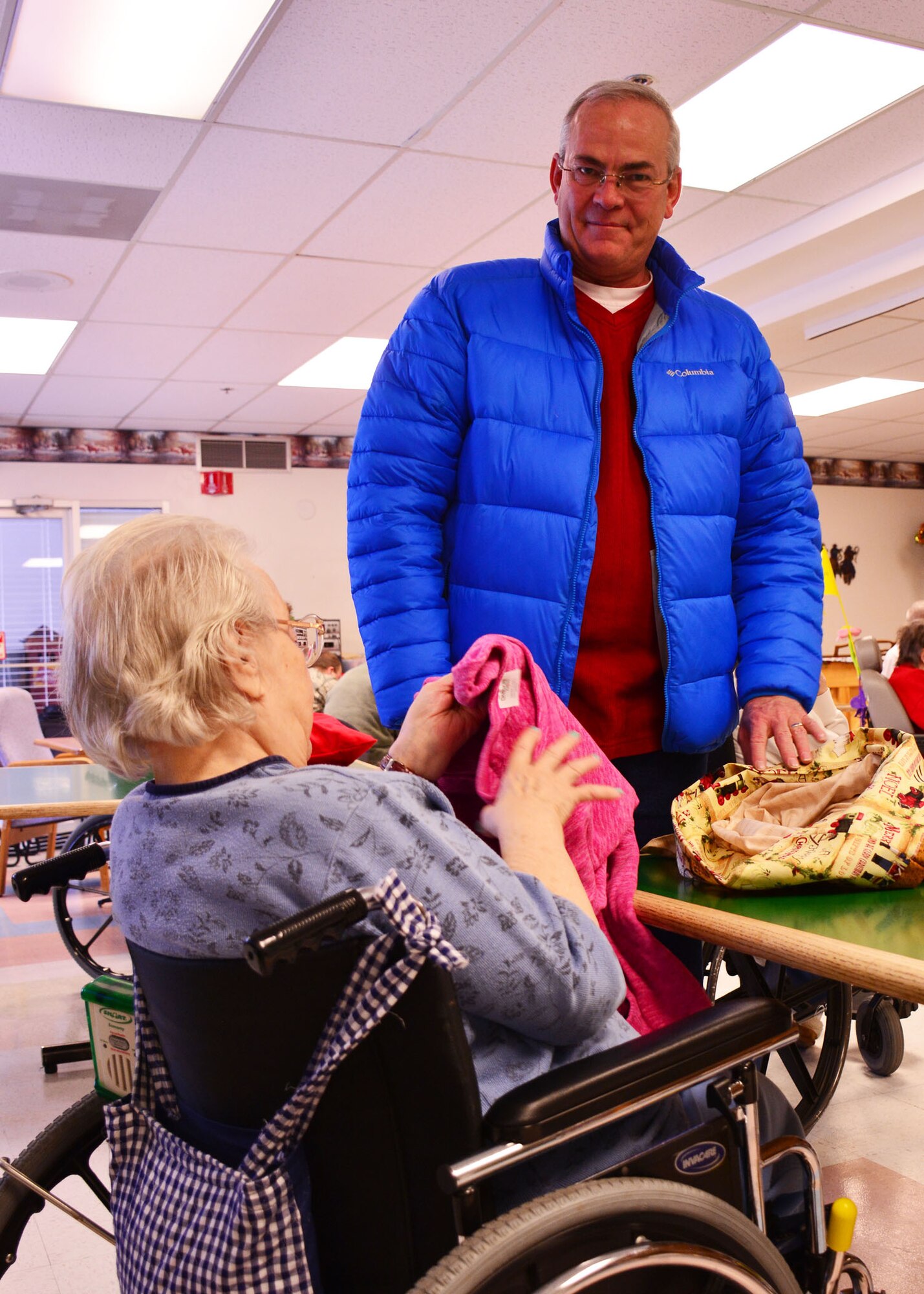 120th Logistics Readiness Squadron retired Master Sgt. Marty Graham presents a gift to a resident of the Park Place Transitional Care and Rehabilitation Center in Great Falls, Mont. Dec. 18, 2015. Members of the 120th LRS volunteered to provide gifts and spend time visiting with the nursing home residents during the holiday season. (U.S. Air National Guard photo by Senior Master Sgt. Eric Peterson/Released)