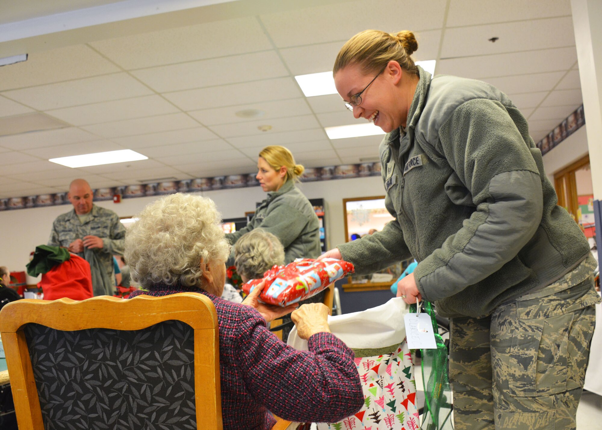 120th Logistics Readiness Squadron Staff Sgt. Cassie DeShaw presents a gift to a resident of the Park Place Transitional Care and Rehabilitation Center in Great Falls, Mont. Dec. 18, 2015. Members of the 120th LRS volunteered to provide gifts and spend time visiting with the nursing home residents during the holiday season. (U.S. Air National Guard photo by Senior Master Sgt. Eric Peterson/Released)