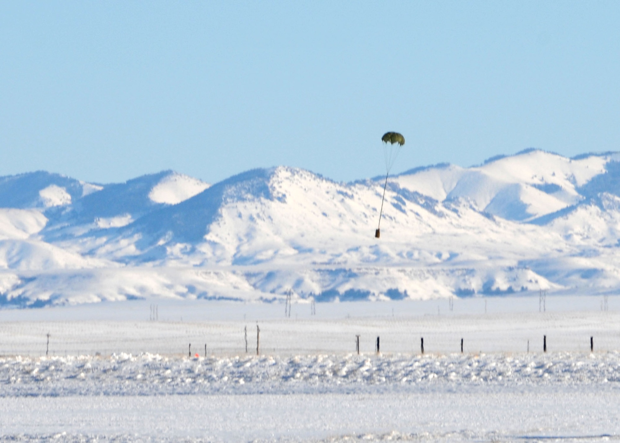 A parachuted training bundle dropped by a C-130 Hercules transport aircraft assigned to the 120th Airlift Wing of the Montana Air National Guard drifts to the ground near the target at the Charging Charlie Drop Zone located at Malmstrom Air Force Base, Mont. Dec. 17, 2015. (U.S. Air National Guard photo by Senior Master Sgt. Eric Peterson/Released)