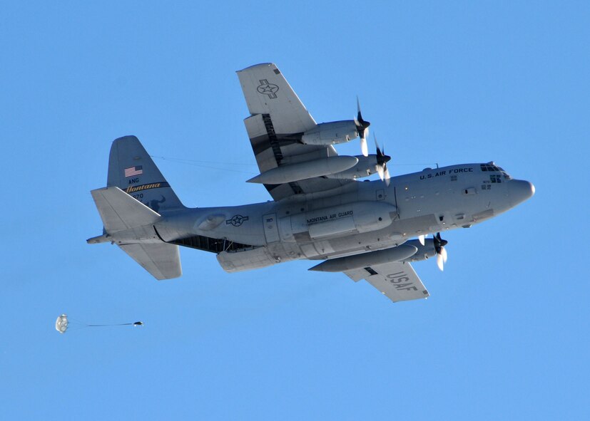 A C-130 Hercules transport aircraft assigned to the 120th Airlift Wing of the Montana Air National Guard drops a parachuted training cargo bundle at the Charging Charlie Drop Zone located at Malmstrom Air Force Base, Mont. Dec. 17, 2015. (U.S. Air National Guard photo by Senior Master Sgt. Eric Peterson/Released)